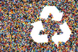Colourful plastic pellets with recycling symbol.
